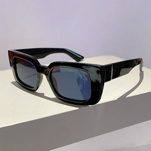 Detail view of vintage black square thick frame sunglasses on a geometric white pedestal