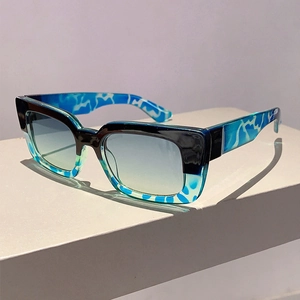 Detail of square sunglasses with dual-tone frames and gradient lenses on a pedestal