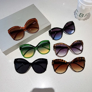 Chic oversized butterfly sunglasses in various gradient colors on minimalist grey steps