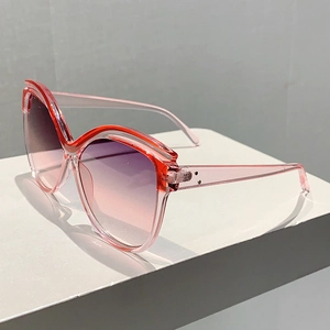 Macro detail of oversized butterfly sunglasses with red gradient frame and silver rivets