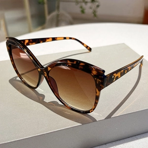 Close-up of leopard print butterfly sunglasses with brown gradient lenses on display