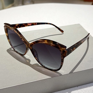 Detail showing tortoise shell frame pattern and dual metal rivets on cat eye sunglasses
