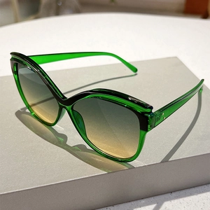 Close-up of cat-eye sunglasses with green transparent frames and gradient lenses