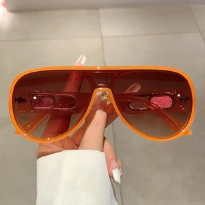 Detail of orange aviator sunglasses featuring gradient brown lenses and a resin frame