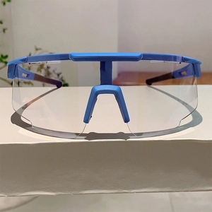 Close-up of blue sports cycling goggles with clear lenses on a white display stand