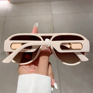 Detail of cream beige oversized sunglasses with brown lenses and golden metal accents