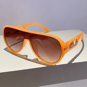 Detail of orange oversized sunglasses with brown gradient lenses and gold temple accents