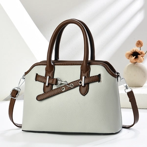 Macro detail of beige lychee grain texture and brown leather strap on shell handbag