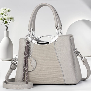 Detailed view of grey lychee leather handbag with woven tassel and silver hardware