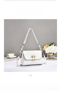 Detail of white glossy PU crossbody bag with golden swan hardware and tassel detail