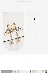 Detailed view of the gold twin swan buckle with crystal heart and pearl charms on a bag