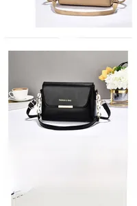 Detail of black crossbody bag with gold lettering and mixed leather-chain strap