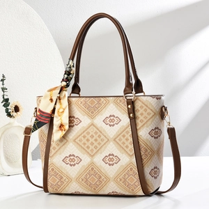 Detail of a beige woven tote bag with brown geometric patterns and a silk scarf accent