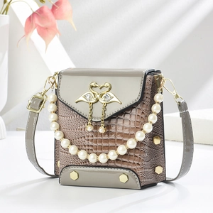 Close-up of a mini handbag featuring crocodile texture and a golden swan clasp with pearls