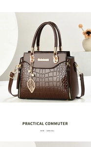 Detail of dark brown crocodile embossed leather handbag with golden logo and pearl charm