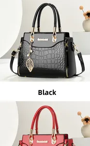 Detail of crocodile embossed leather handbag with gold leaf charm and pearl accent