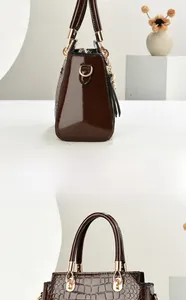 Detail of brown crocodile pattern patent leather handbag with gold hardware and pearl charm