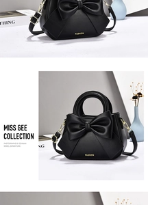 Detailed view of black leather handbag with oversized bow and gold FASHION lettering