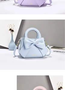 Detail view of light blue leather bag with large bow and golden metal hook hardware