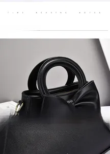 Close-up of the stitching craftsmanship on a black handbag with bow and round handle