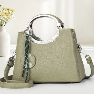 Sac à main élégant en cuir vert avec poignée métallique et breloque tressée chic
