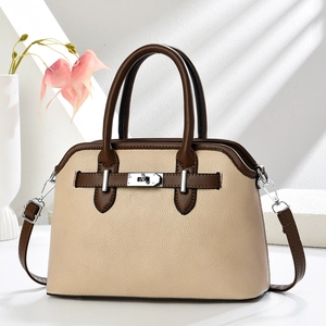 Elegant apricot crossbody bag with brown handles and silver lock shown in minimalist studio