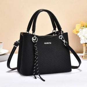 Elegante borsa nera testurizzata con manici e tracolla regolabile in un contesto lifestyle