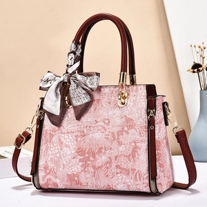 Pink floral jacquard handbag with silk scarf handle and adjustable strap in elegant setting
