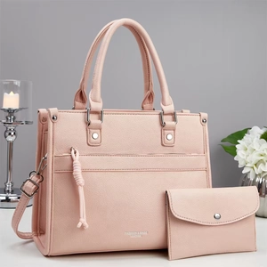Detail of pink lychee leather handbag set with tassels and silver studs in a minimalist setting