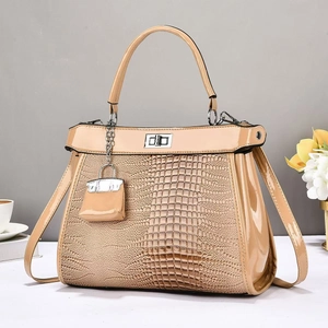 Close-up of khaki crocodile-embossed handbag featuring a silver twist lock and mini charm