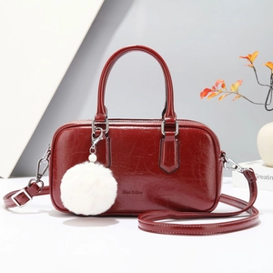 Elegant deep red Boston handbag in glossy leather with a fluffy white charm