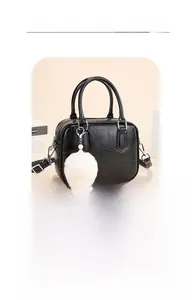 Close-up of vintage black PU leather shoulder bag with textured surface and white pompom