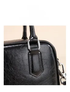 Detail of the reinforced handle connection with metal buckles on a black PU leather bag