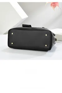 Nahaufnahme von schwarzer Lederhandtasche mit goldenen Schutzfüßen und geometrischer Prägung