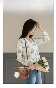 Brown lychee-patterned bowling bag with white plush charm and adjustable strap