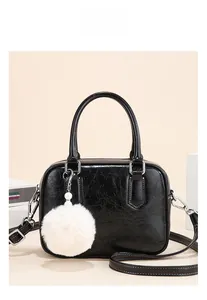 Detail of black oil wax leather tote bag with plush ball charm and silver hardware