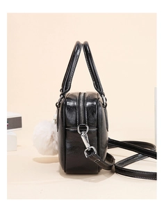 Detail of glossy black bowling handbag with silver zipper and white plush pearl charm