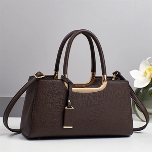 Détail du sac à main en cuir marron foncé avec texture litchi et poignées dorées