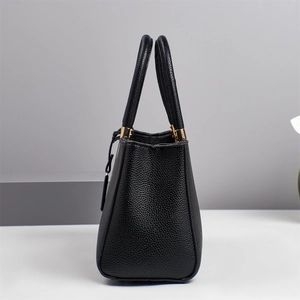 Détail du sac à main noir en cuir grainé avec poignées rondes et accents dorés