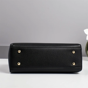 Détail de la base d'un sac en cuir noir avec clous de protection en métal doré