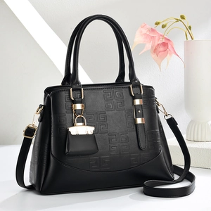 Schwarze Umhängetasche mit geometrischer Prägung und Golddetails vor weißem Hintergrund
