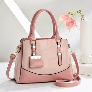 Rosa Patchwork-Handtasche mit geometrischer Prägung und Mini-Anhänger in Studio-Umgebung