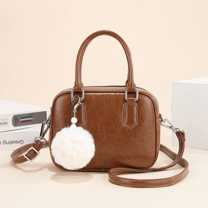 Brown pleated leather bowling bag with plush pompom on a minimalist beige background