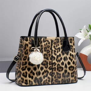 Detail of leopard print handbag with black patent leather trim and white pompom charm