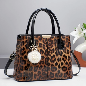 Detail of leopard print handbag with glossy leather finish and faux fur pompom charm