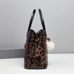 Detail of leopard print handbag with black handles and white fluffy pearl charm