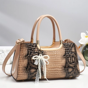 Detail of beige snakeskin textured handbag with pearl bow pendant and lace trim