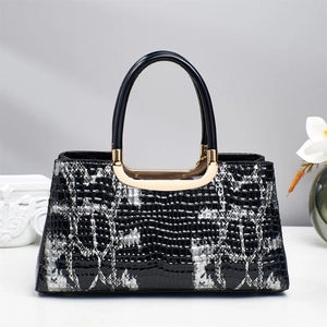 Detail of luxury snakeskin texture handbag with sleek round handles and gold metallic accents