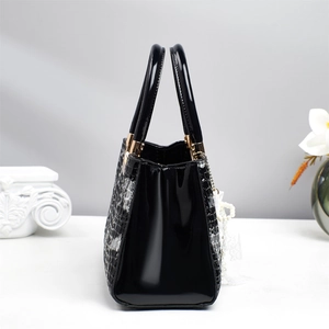 Detail of black patent leather handbag with textured pattern and pearl lace pendant