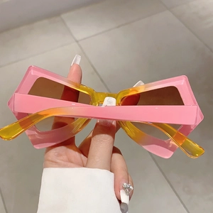 Detail of trendy butterfly sunglasses with pink-yellow gradient frame and dark brown lens